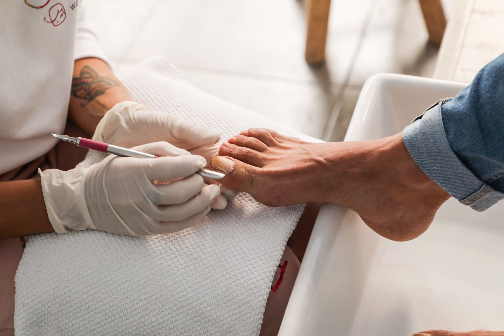 Podologin führt eine sorgfältige Nagelbehandlung mit Handschuhen durch